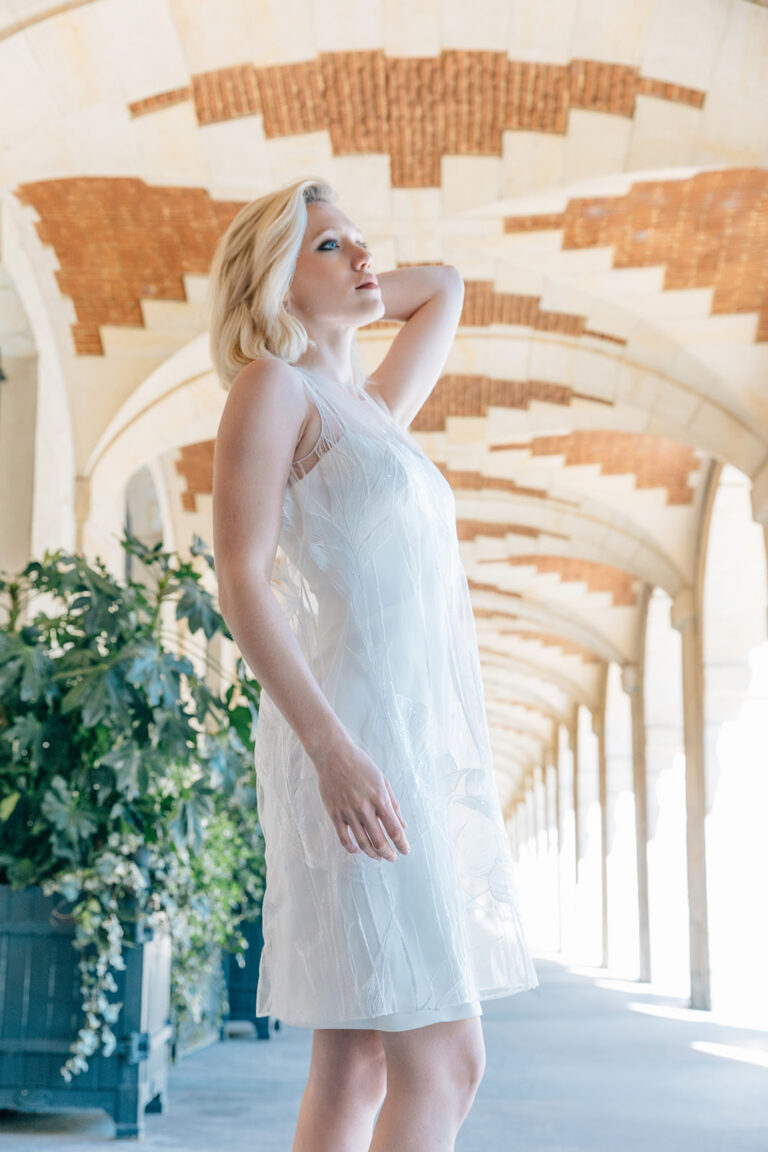 Femme dans la rue qui porte une robe de mariée court et un top en tulle brodé.
