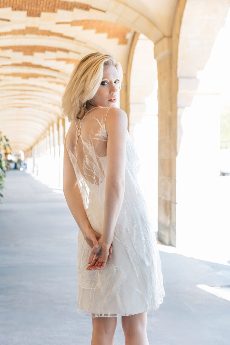 Femme dans la rue qui porte une robe de mariée court et un top en tulle brodé.