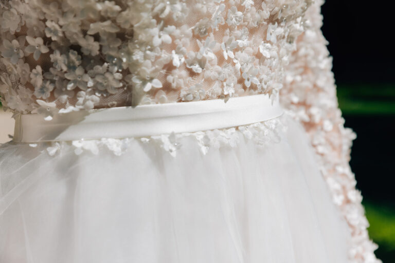 Gros plan sur les détails d'une robe de mariée en tulle, avec une jolie ceinture en satin.