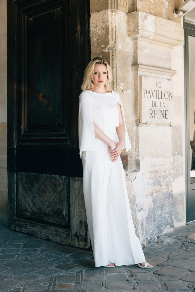 Femme portant une tenue de mariée blanche avec un pantalon ample et une cape