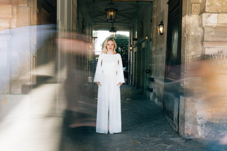 Femme portant une tenue de mariée blanche avec un pantalon ample et une cape