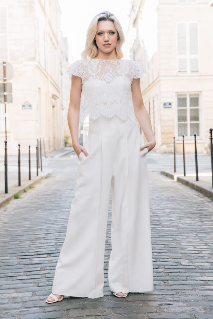 Femme dans tenue de mariée avec un pantalon blanc et un top blanc en dentelle de Calais-Caudry