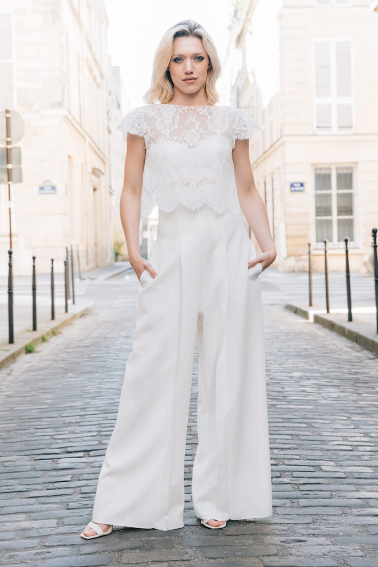Femme dans tenue de mariée avec un pantalon blanc et un top blanc en dentelle de Calais-Caudry