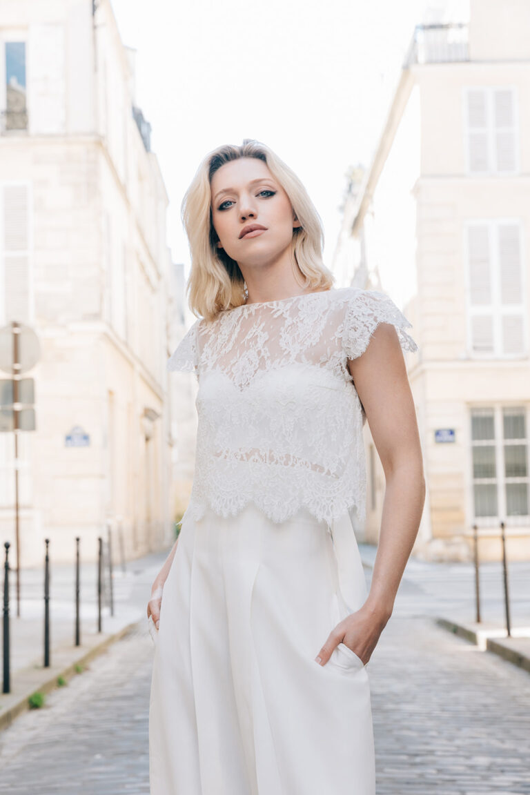Femme dans tenue de mariée avec un pantalon blanc et un top en dentelle de Calais-Caudry