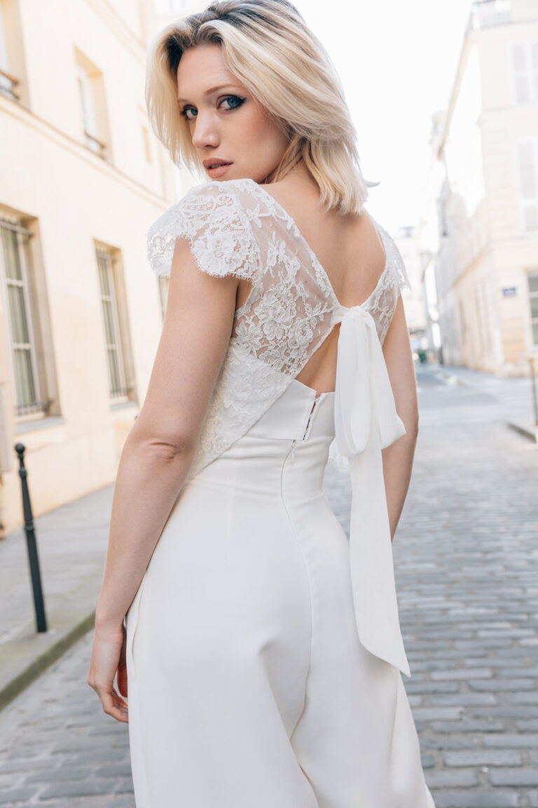 Femme portant une tenue de mariée blanche avec un top en dentelle de Calais-Caudry qui se noue dans le dos.