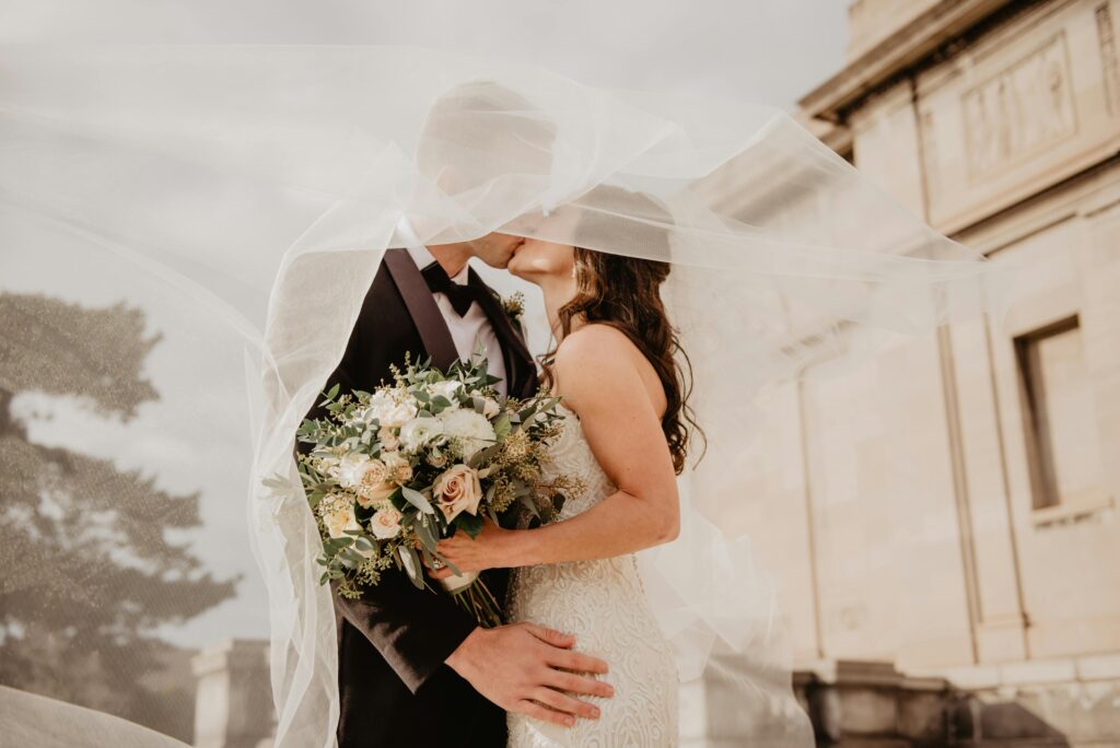 mariage, couple qui s'embrasse, bouquet de fleurs, voile et robe blanche