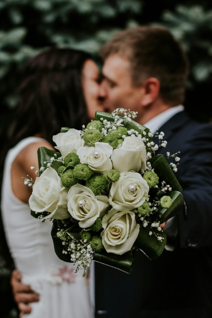 un couple de marié s'embrasse à leur mariage. le bouquet de la mariée